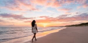 Como Vencer o Cansaço Emocional e Limites - Pessoa caminhando sozinha na praia ao amanhecer, representando o autocuidado e o alívio do peso da hiper-responsabilidade.